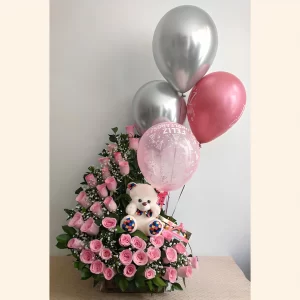 Oso de peluche blanco sentado entre rosas rosadas, con globos plateados y rosados de Feliz Cumpleaños.